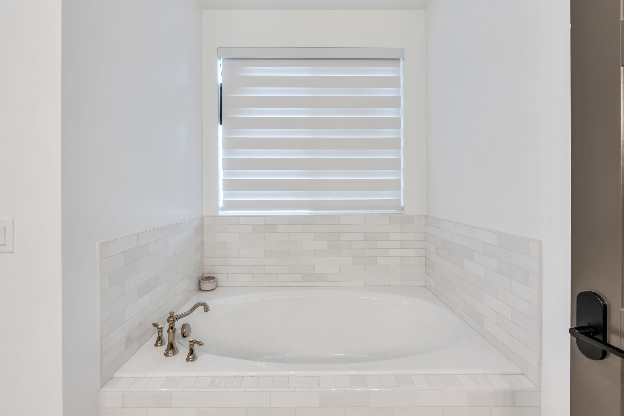 Built-in soaking tub featuring a decorative tile surround and wall wainscoting