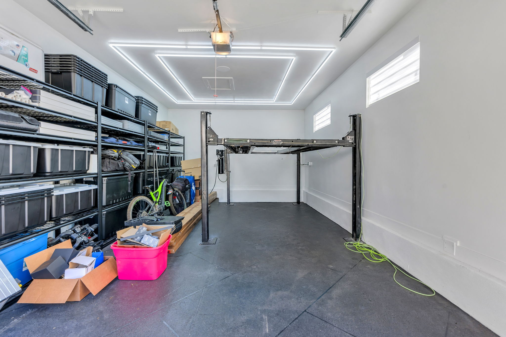 Garage space featuring a car lift, square overhead lighting, and two high-set windows