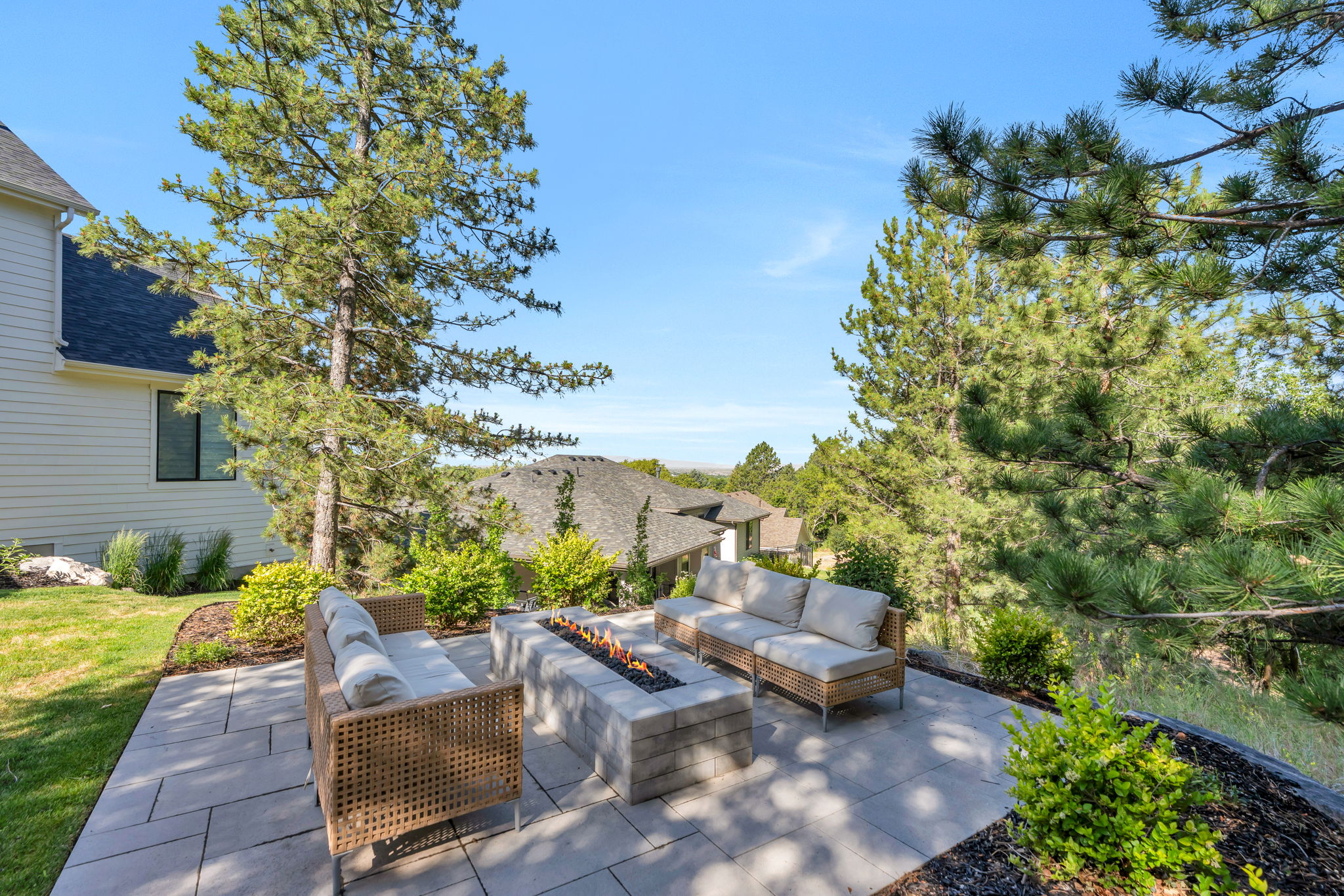 Spacious patio featuring large format pavers and a built-in stone fire pit