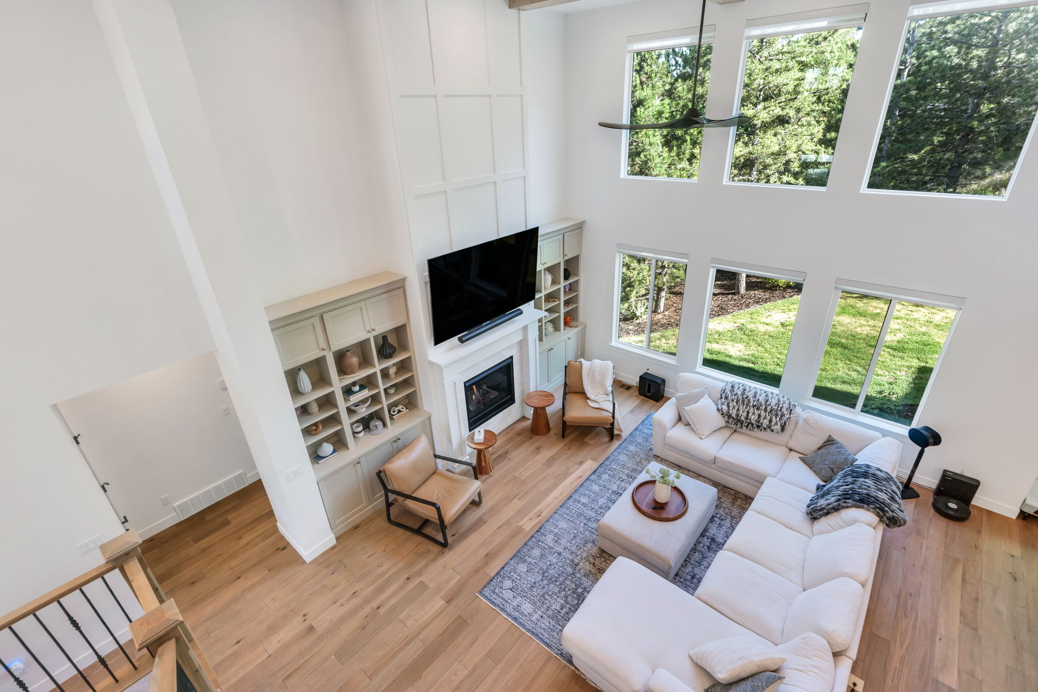 Spacious living area featuring high ceilings, wood-finish flooring, a contemporary fireplace, and built-in cabinetry with shelving