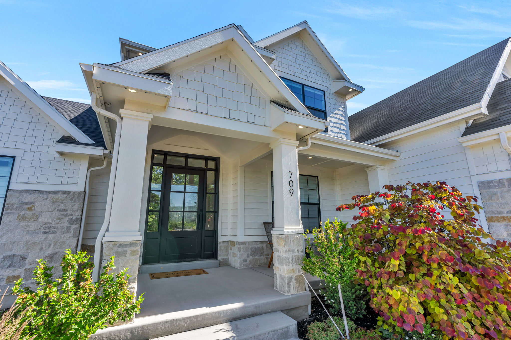 Inviting covered entry with stone pillars and a dark-paneled glass door
