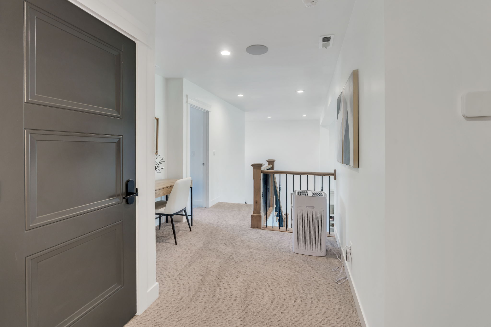 White walls with recessed lighting illuminate a carpeted hallway