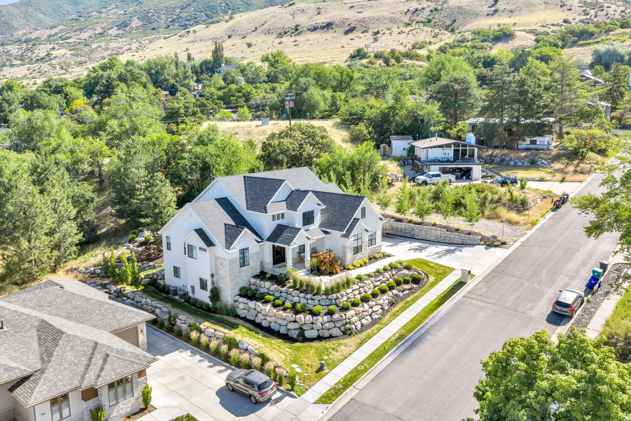 Modern-style residence featuring a multi-gabled roofline and a combination of white siding with stone accents