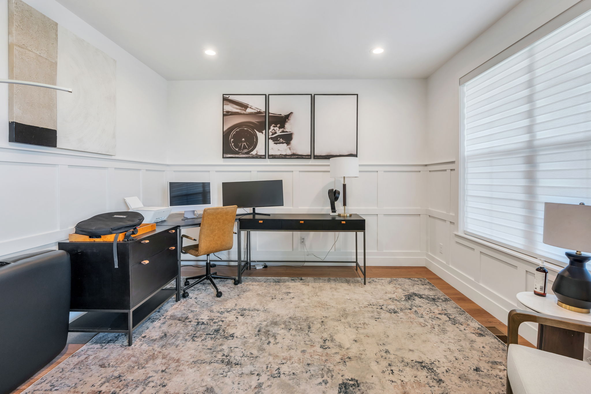 Spacious room featuring white board and batten wall paneling, recessed lighting, a large window with blinds, and wood-finish flooring