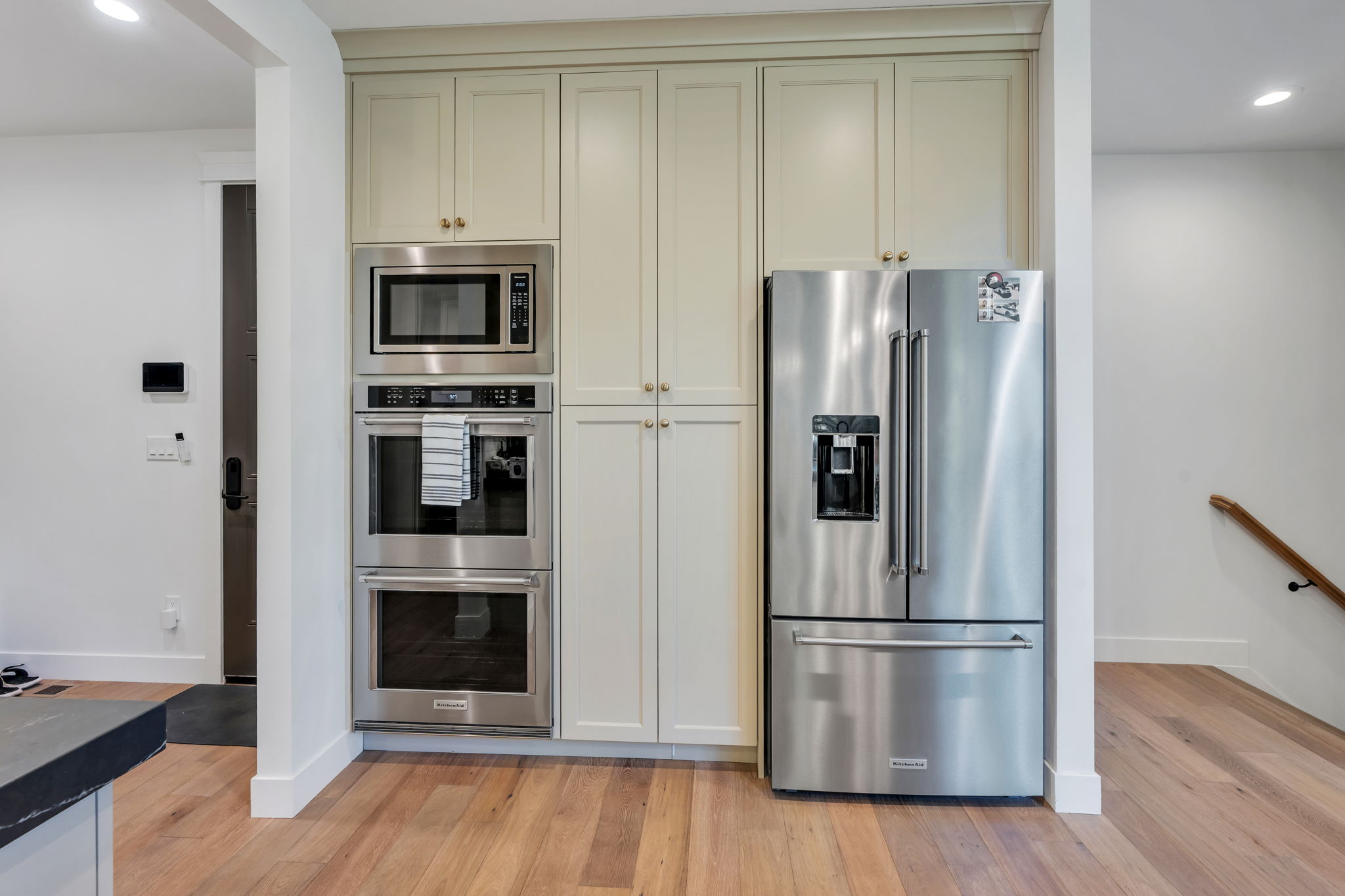 Stainless steel appliances, including a built-in microwave, double oven, and French-door refrigerator, are integrated into custom cabinetry