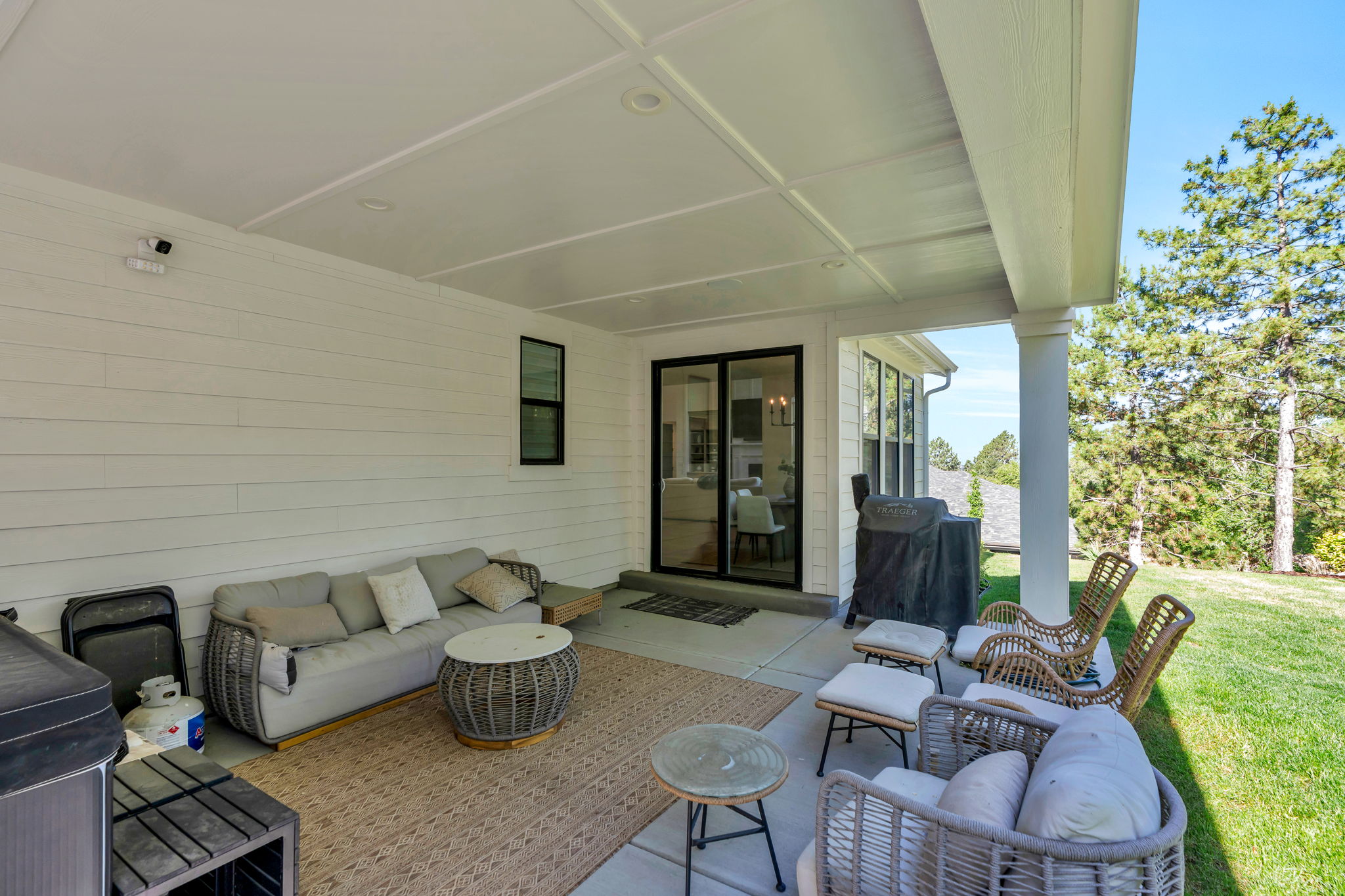 Expansive covered patio featuring a coffered ceiling, concrete flooring, and a crisp white shiplap exterior wall