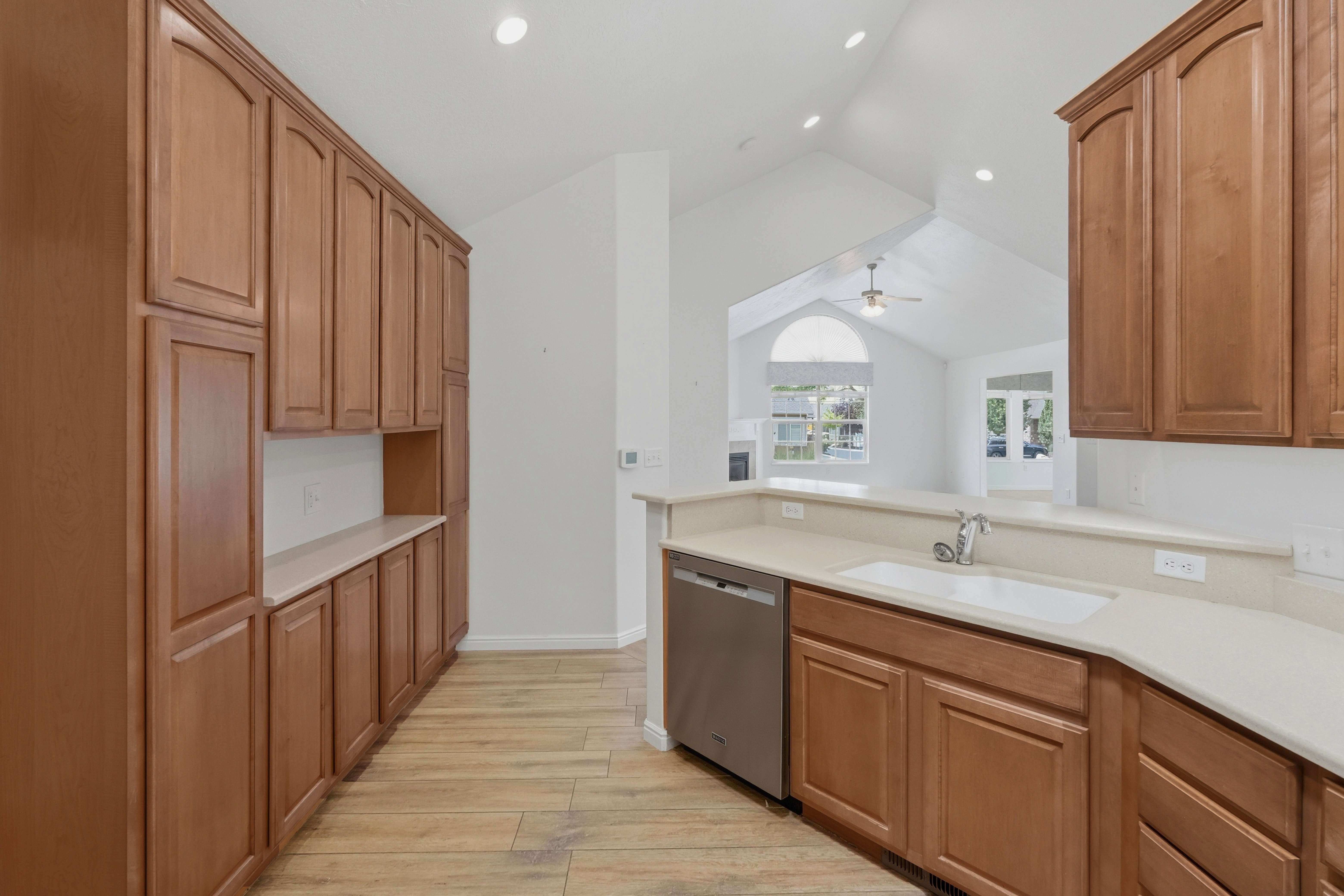 Kitchen featuring wood-finish cabinetry, light-toned countertops, and wood-finish flooring