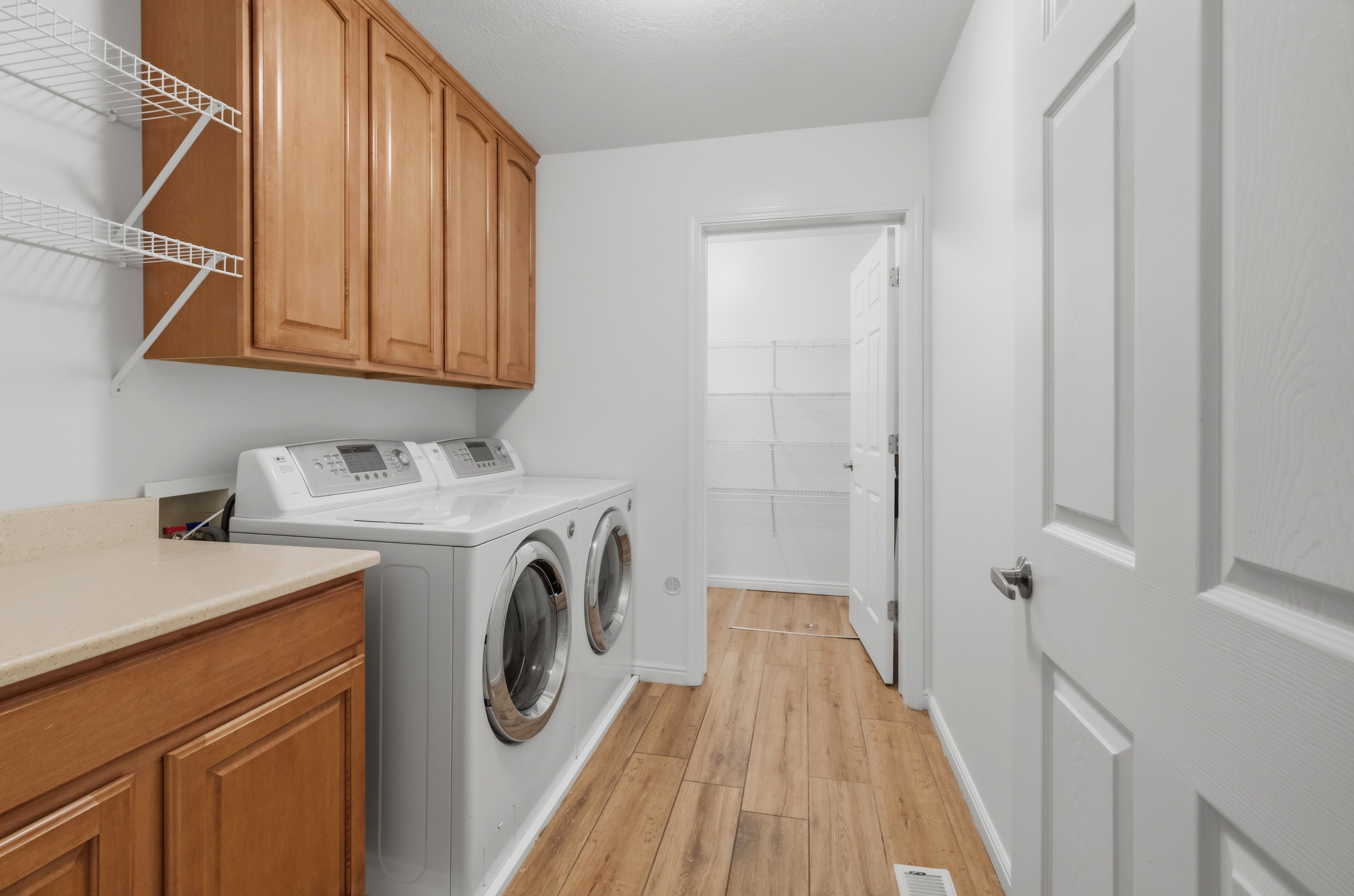 Dedicated laundry space featuring wood-finish flooring, light wood cabinetry, and a countertop for convenience