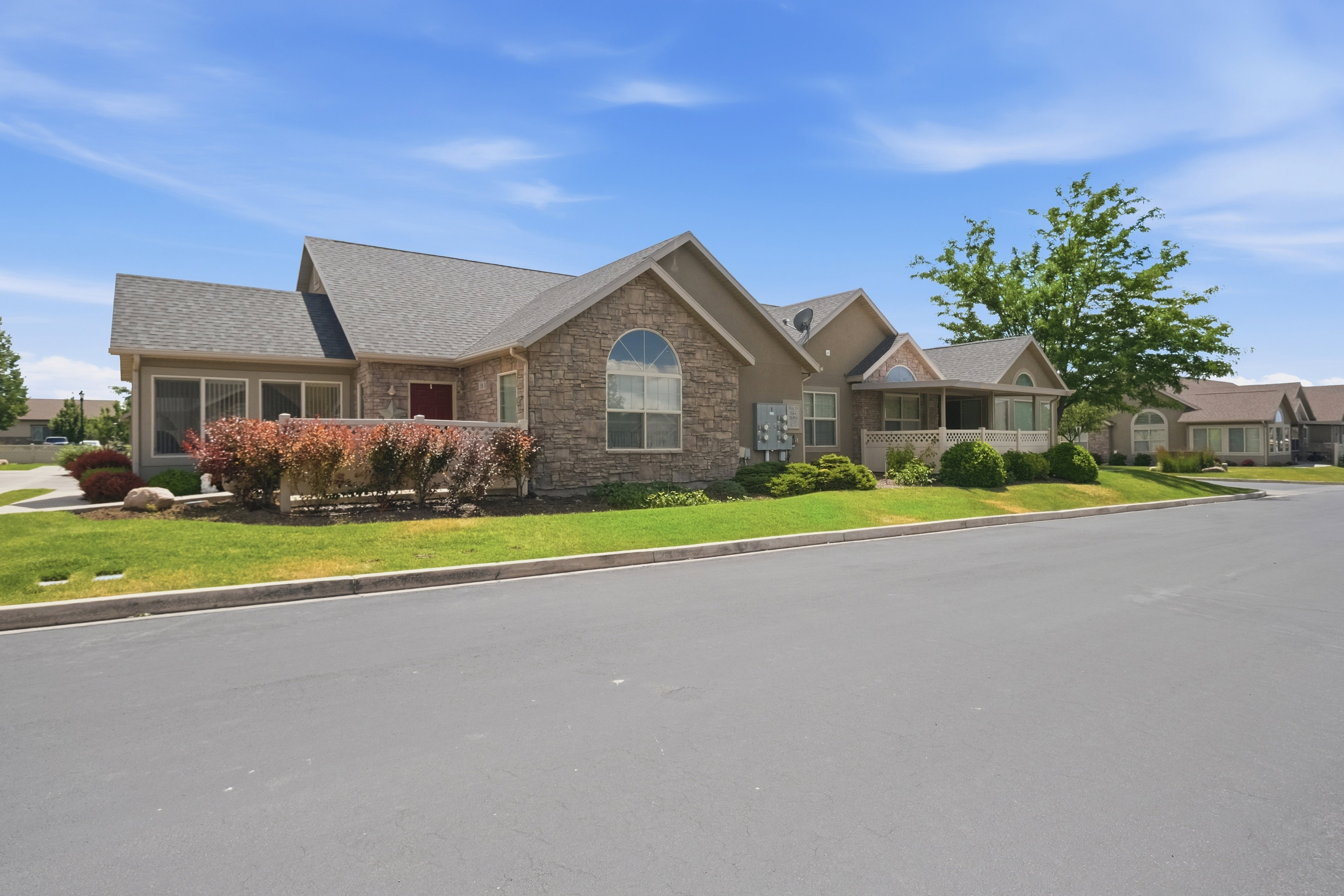 Stone veneer facade with arch-top windows, complemented by a covered front porch and mature landscaping