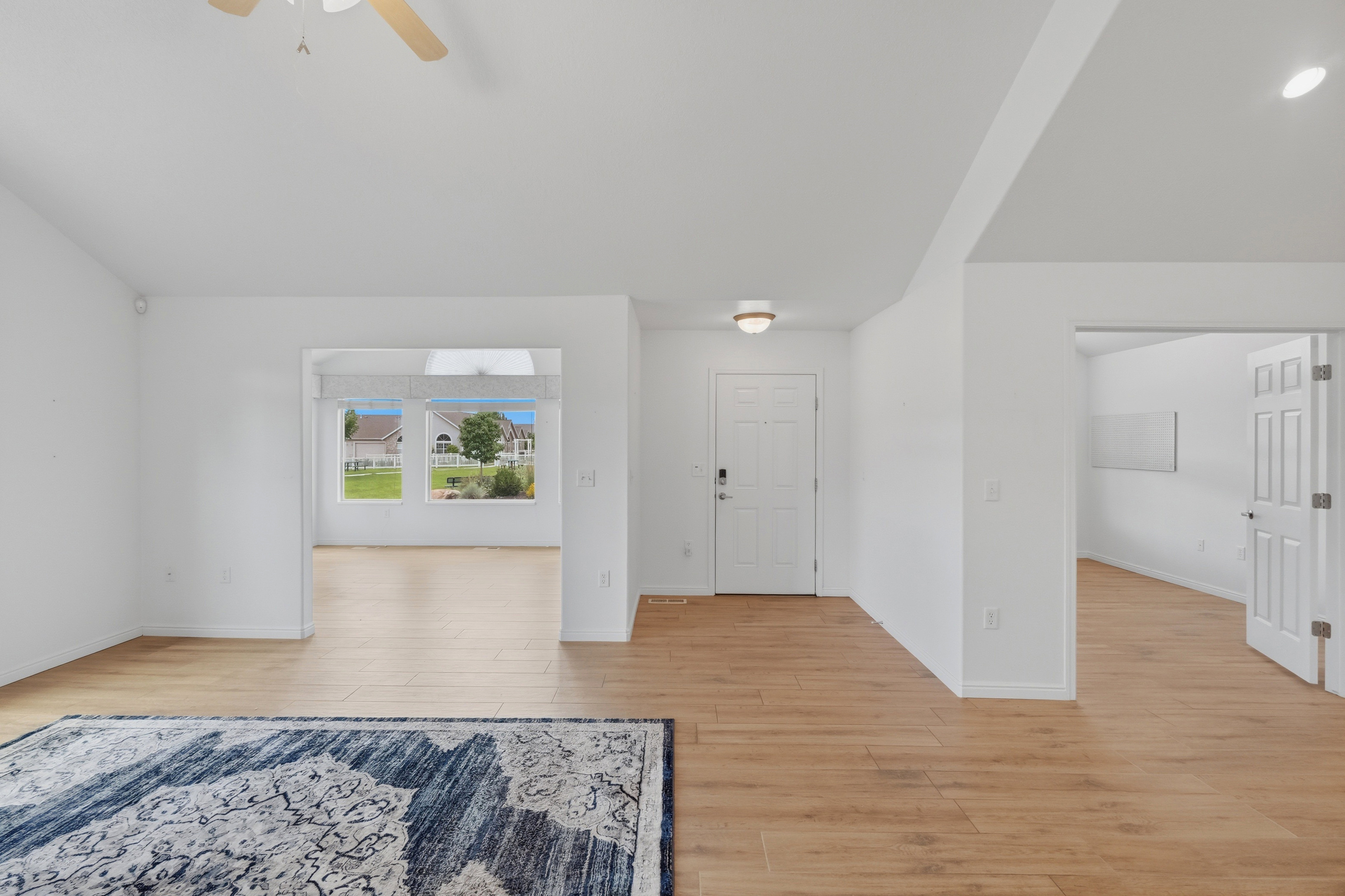 Spacious interior featuring wood-finish flooring, vaulted ceilings, and a ceiling fan