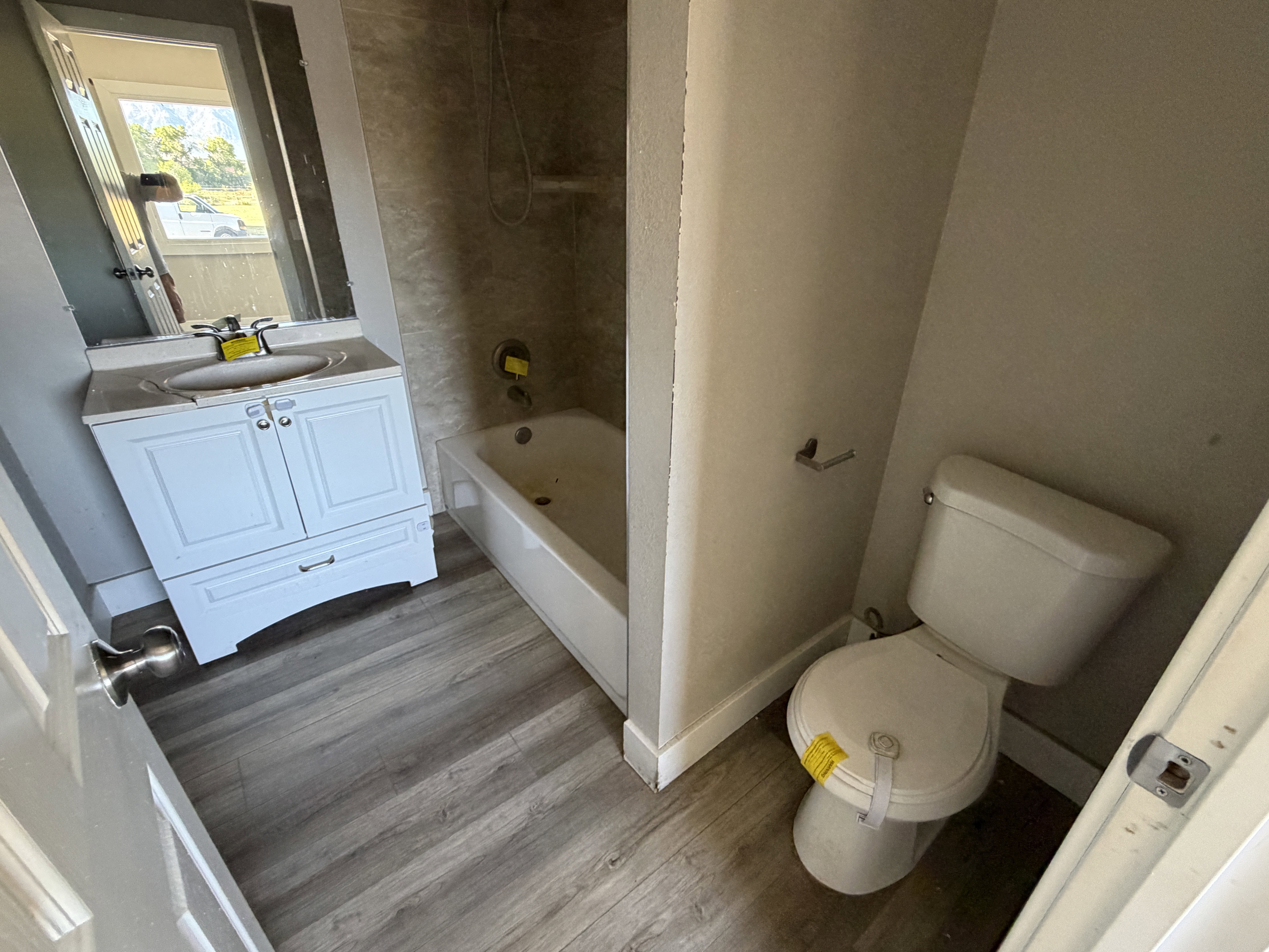 Bathroom featuring wood-finish flooring and a white single-sink vanity with cabinet storage