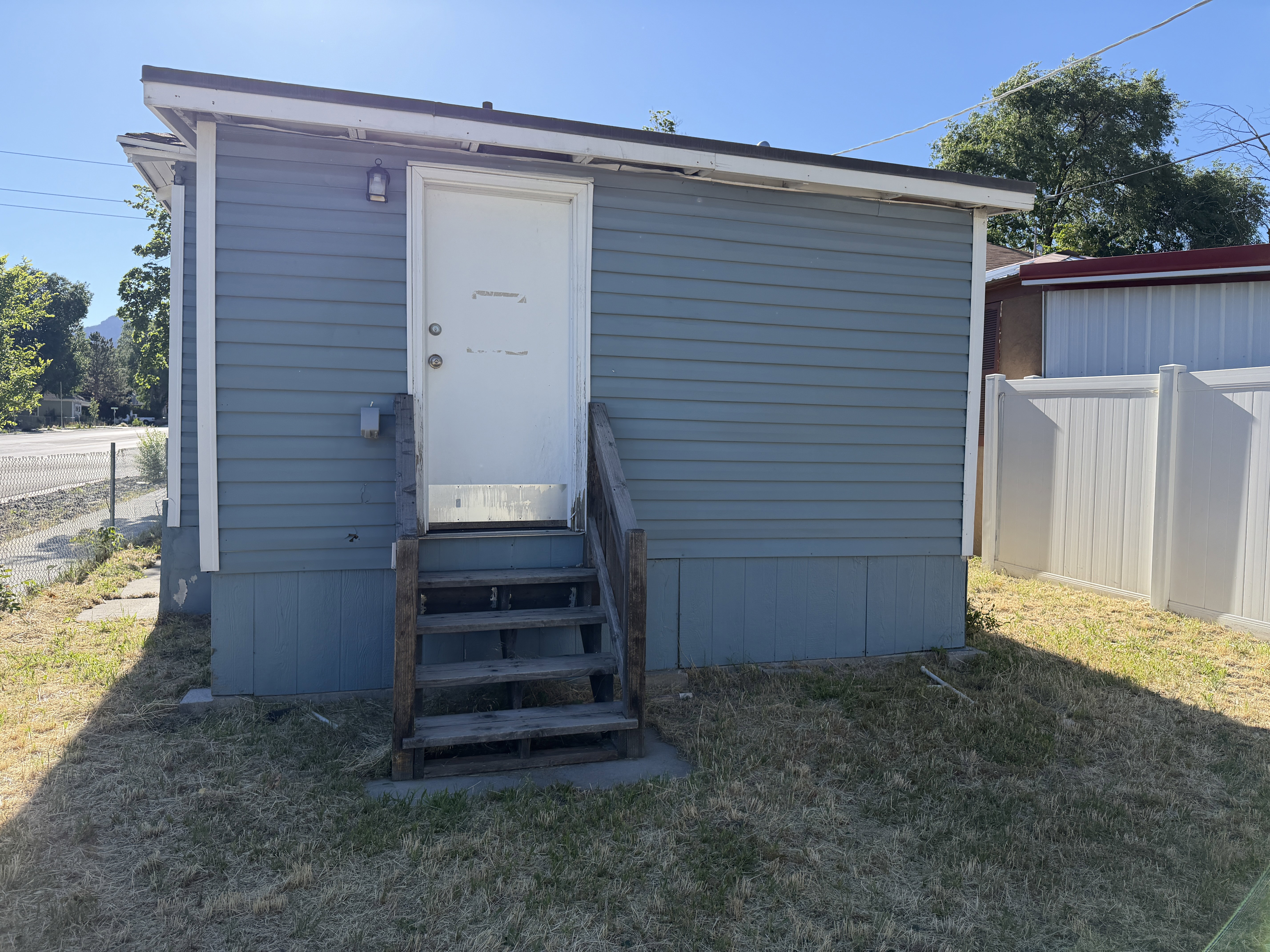 Light blue siding exterior with a white door and wood steps