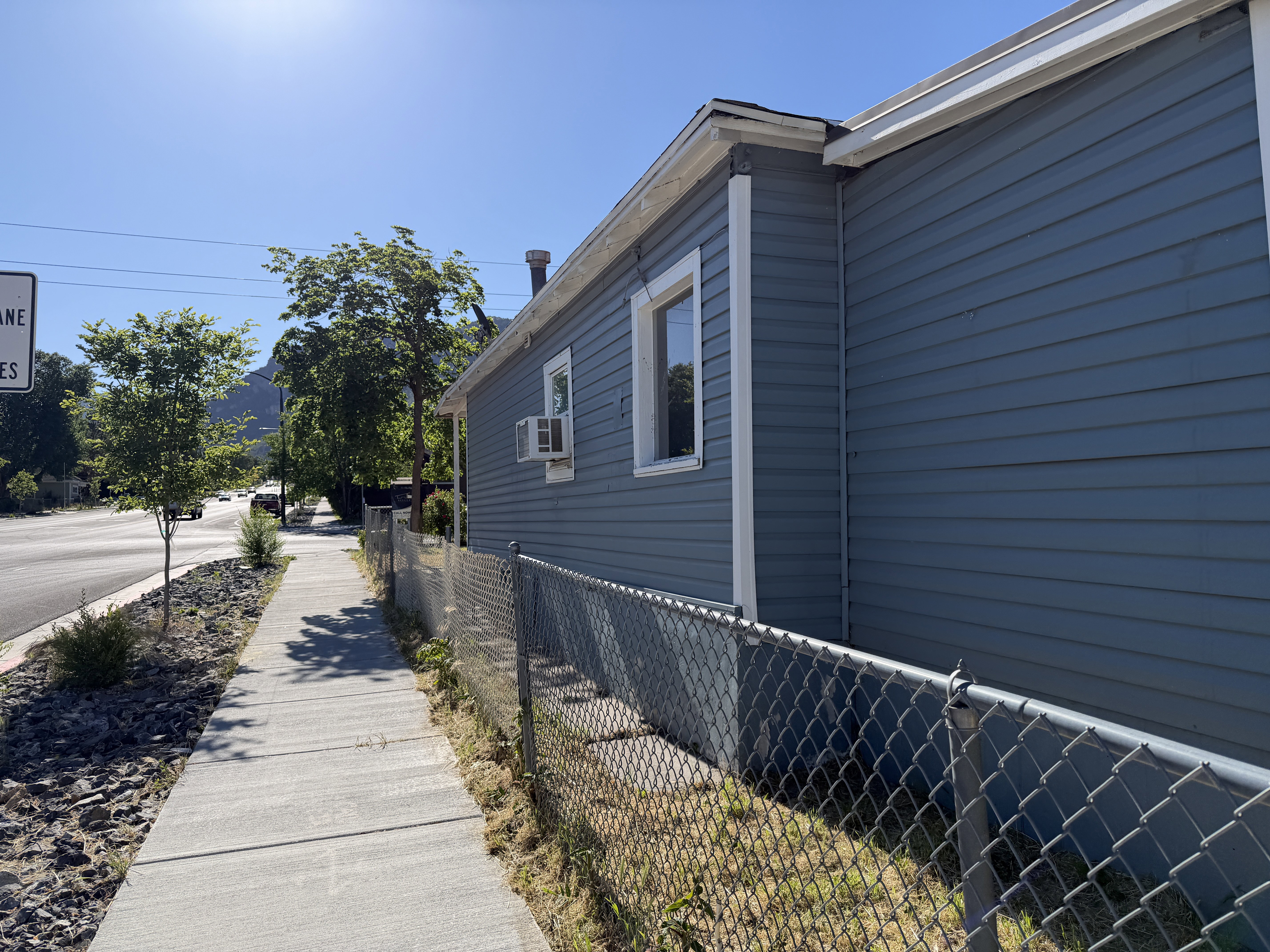 Exterior featuring blue horizontal siding, white trim, and a chain-link fence