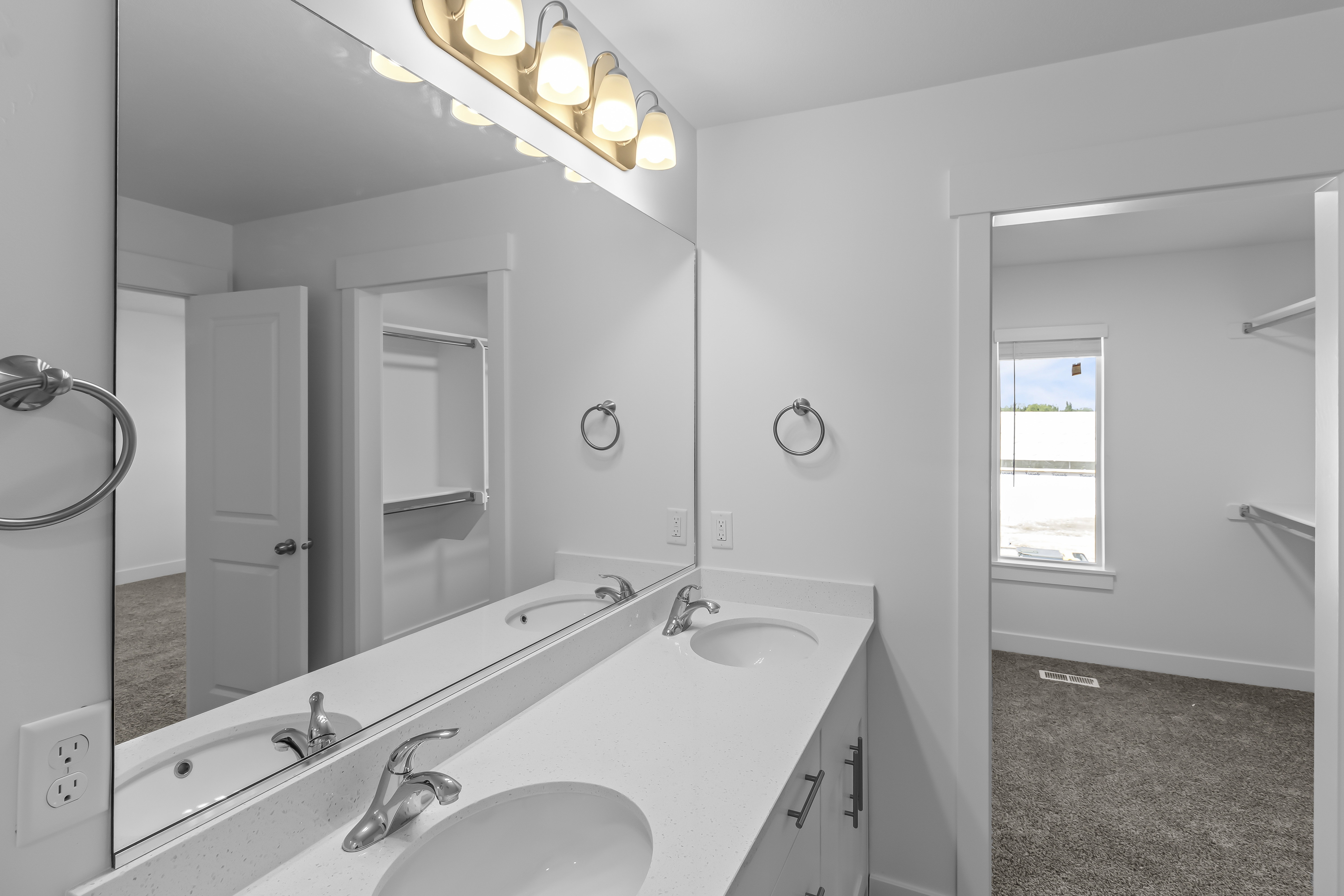 Double vanity with white countertop, chrome fixtures, and overhead lighting