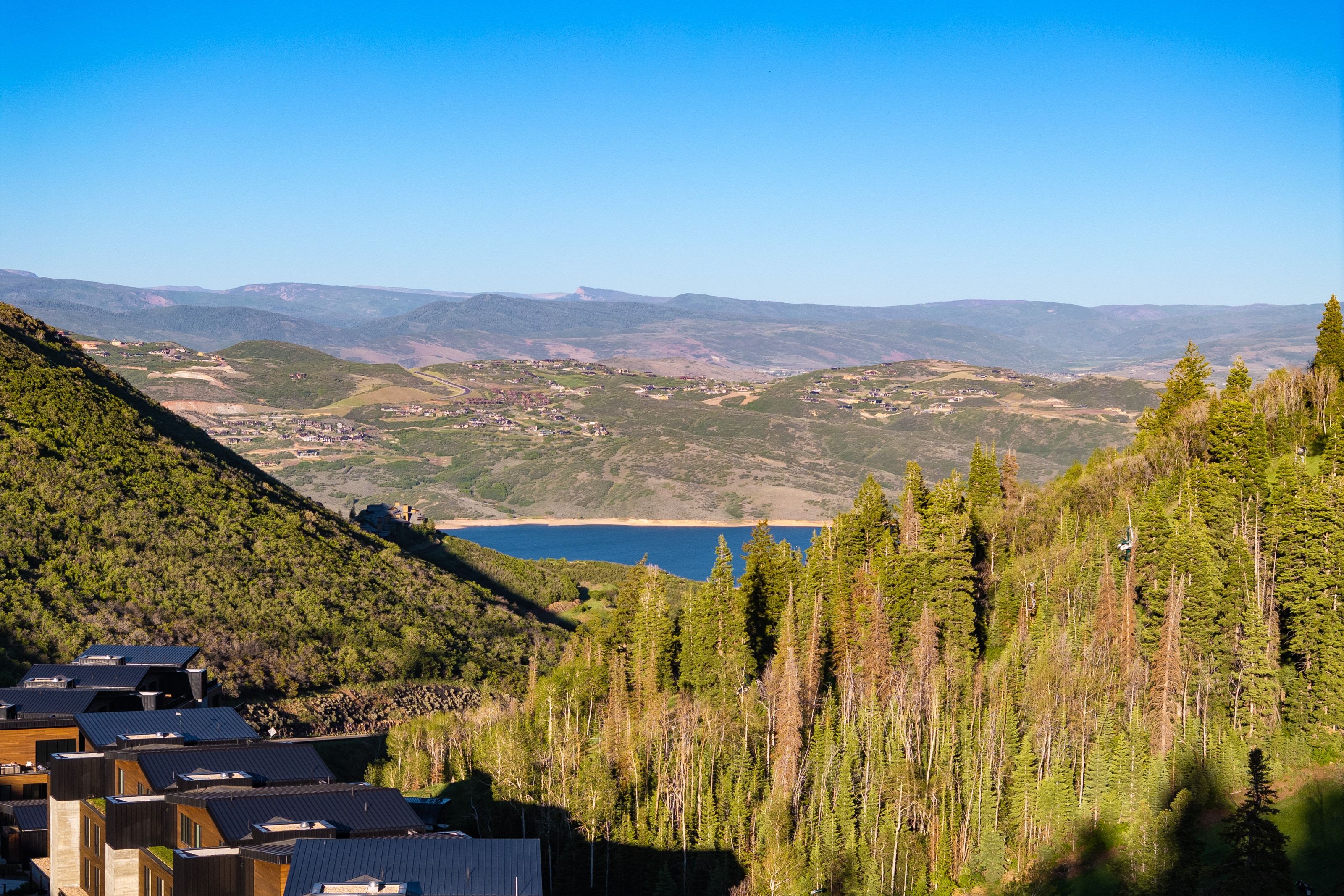 Rolling mountain terrain featuring a prominent body of water, distant hills, and varied tree coverage