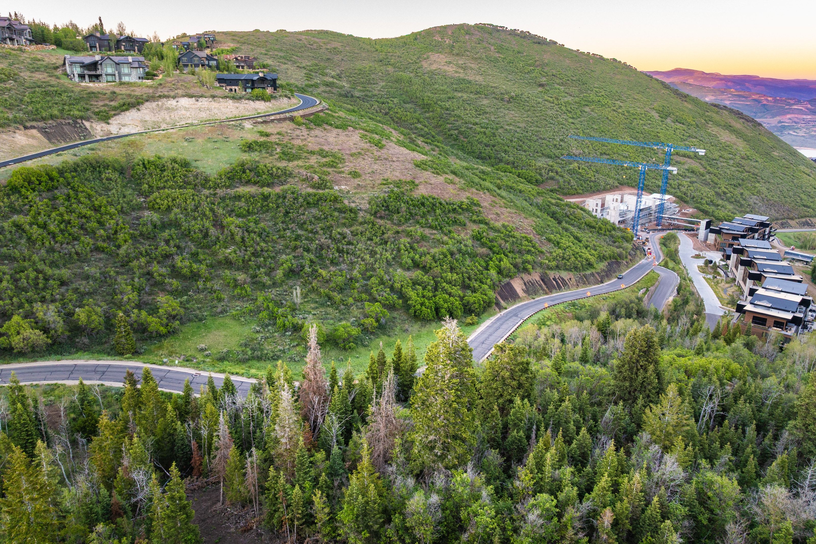 Mountainous terrain featuring winding roadways and lush green vegetation