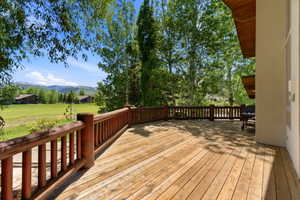 Spacious outdoor deck featuring natural wood decking and a rustic log railing