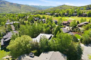 Lush green landscape featuring expansive mountain ranges, surrounding residential properties with varied architectural styles, and a golf course