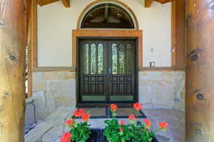 Entryway featuring double doors with decorative glass panels, an arched transom window, and stone veneer accents