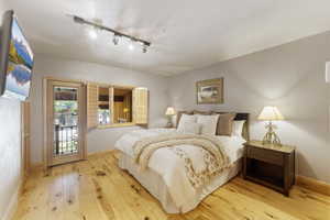 Bedroom featuring light wood-finish flooring and a balcony access door with an ornate black railing