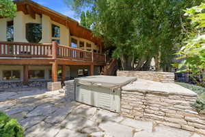 Exterior featuring a log rail deck, flagstone patio, and built-in hot tub