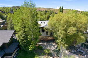 Rear exterior featuring a spacious wood deck, stone retaining walls, and a multi-level stone pathway