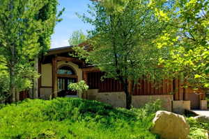 Property entrance featuring a stone facade, wood siding, and prominent wood support beams