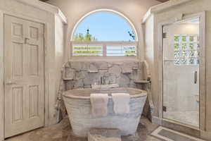 Freestanding stone soaking tub with integrated wall-mounted faucet
