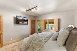 Warm wood-finish flooring complemented by light-colored walls and track lighting