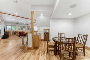 Open-concept space featuring wood-finish flooring, exposed wood beams, and built-in shelving