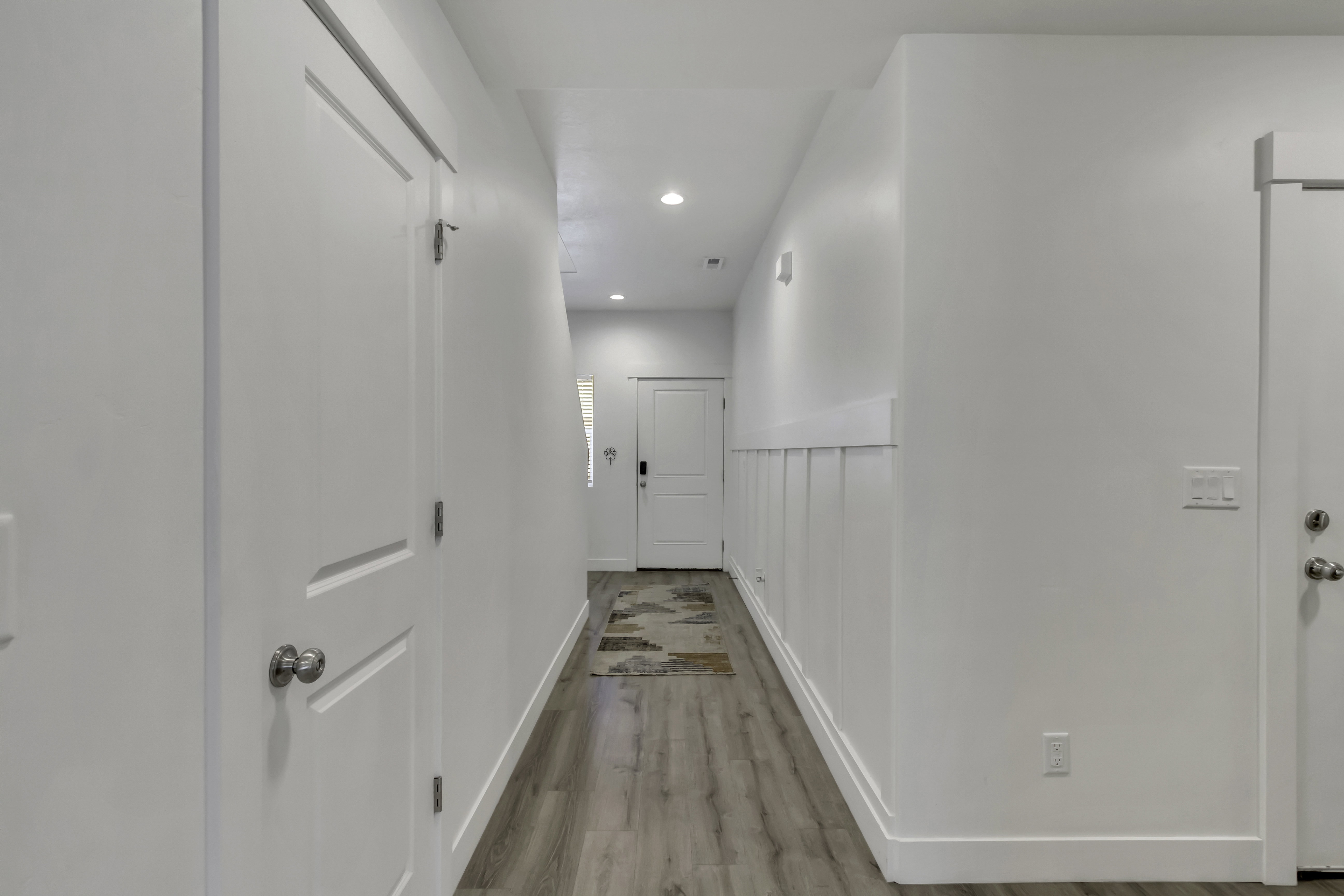 Hallway featuring recessed lighting, wood-finish flooring, white trim, white paneled doors, and board and batten wainscoting