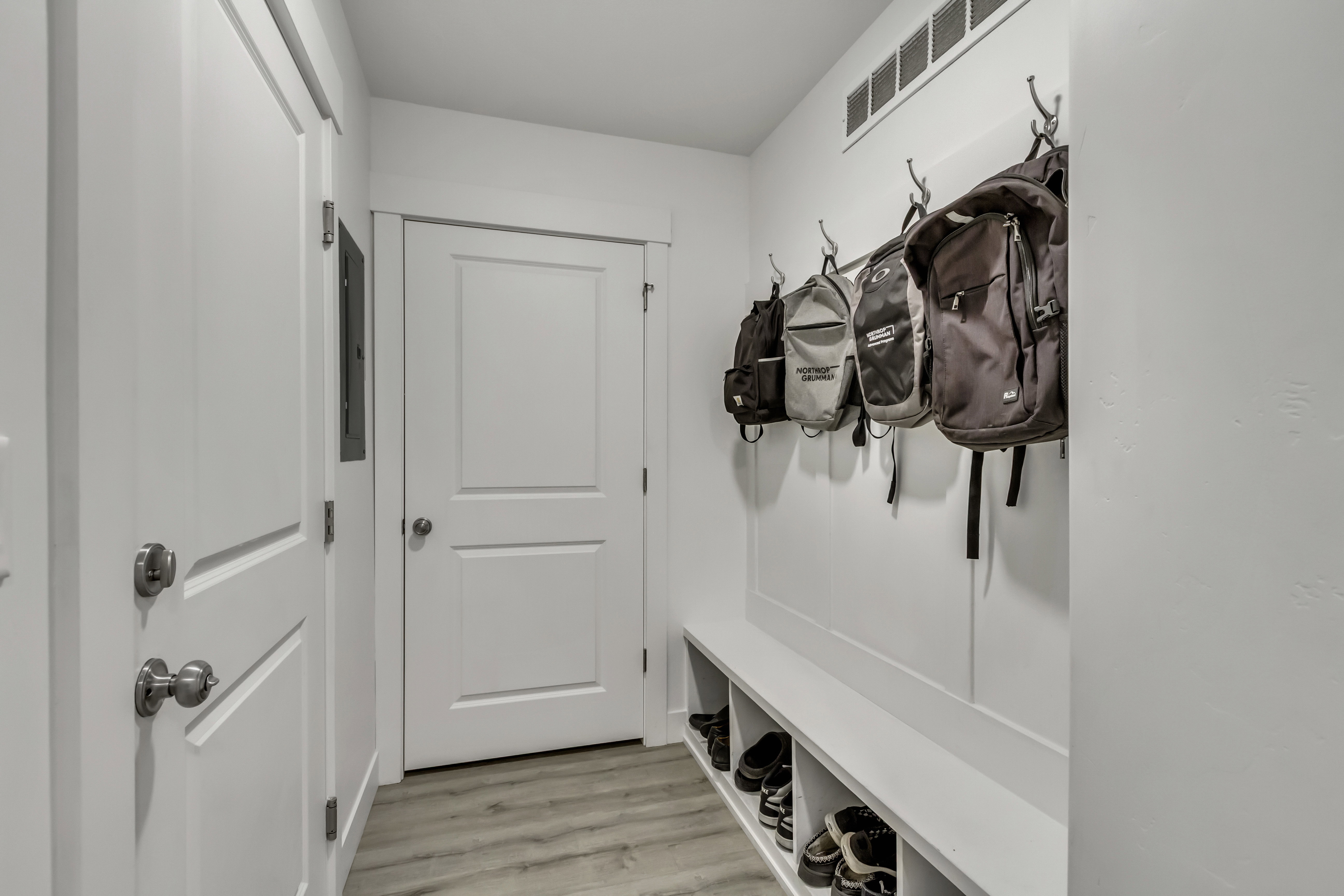 Entryway featuring a built-in bench with integrated shoe cubbies, wall-mounted coat hooks, and light wood-finish flooring