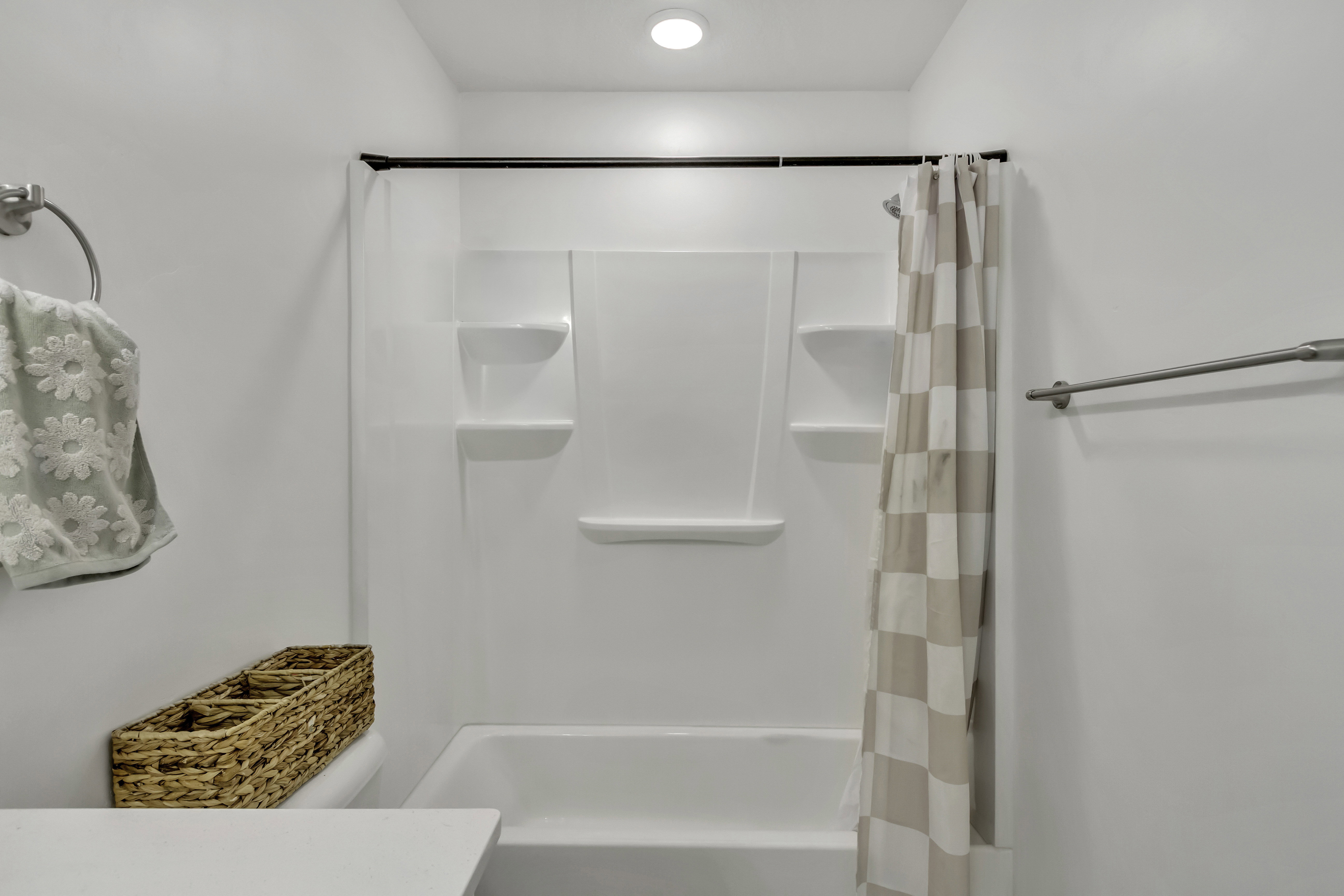 Bathtub and shower combination featuring an integrated white surround with built-in shelving
