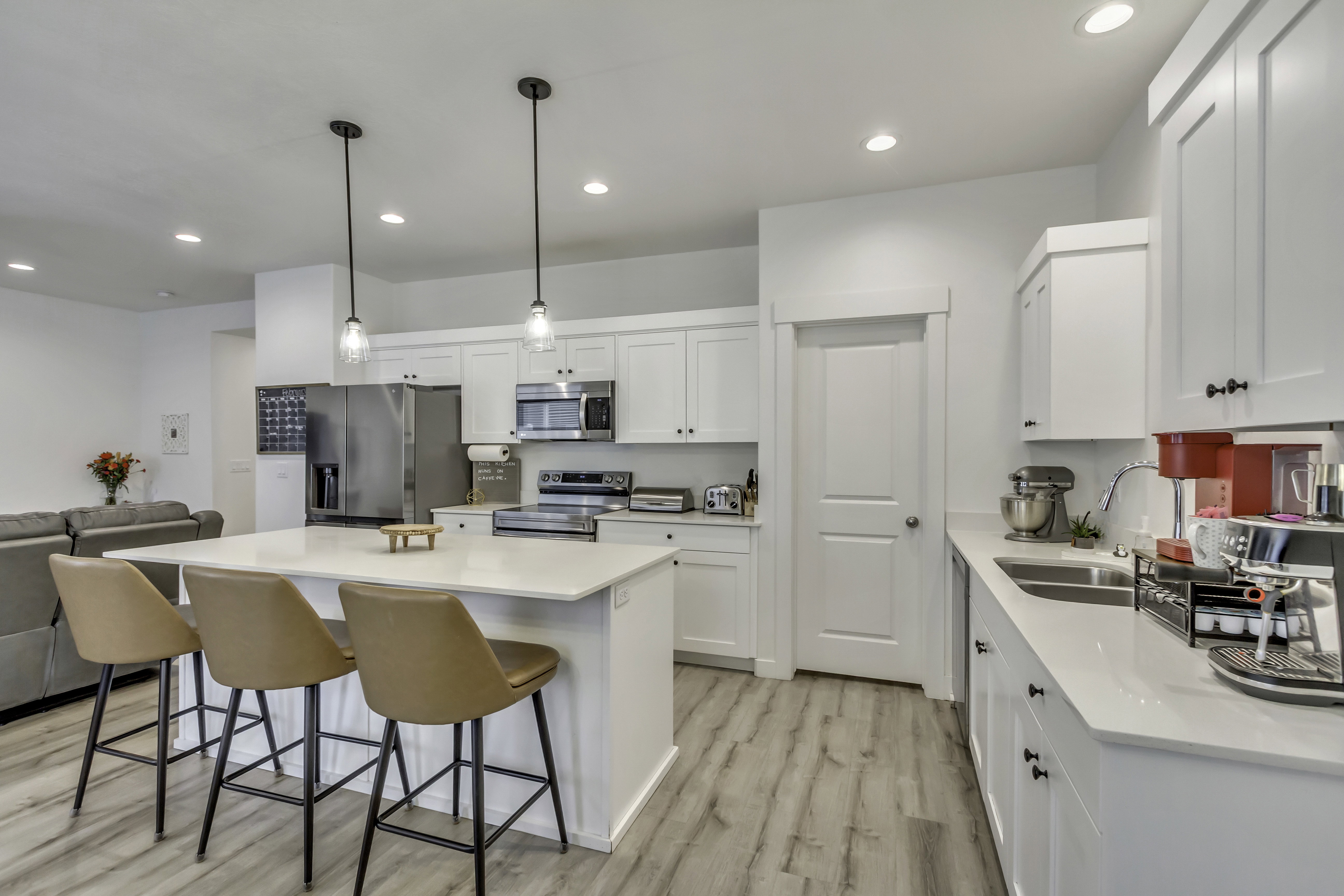 Modern kitchen featuring white shaker cabinetry, stainless steel appliances, a center island with pendant lighting, and wood-finish flooring