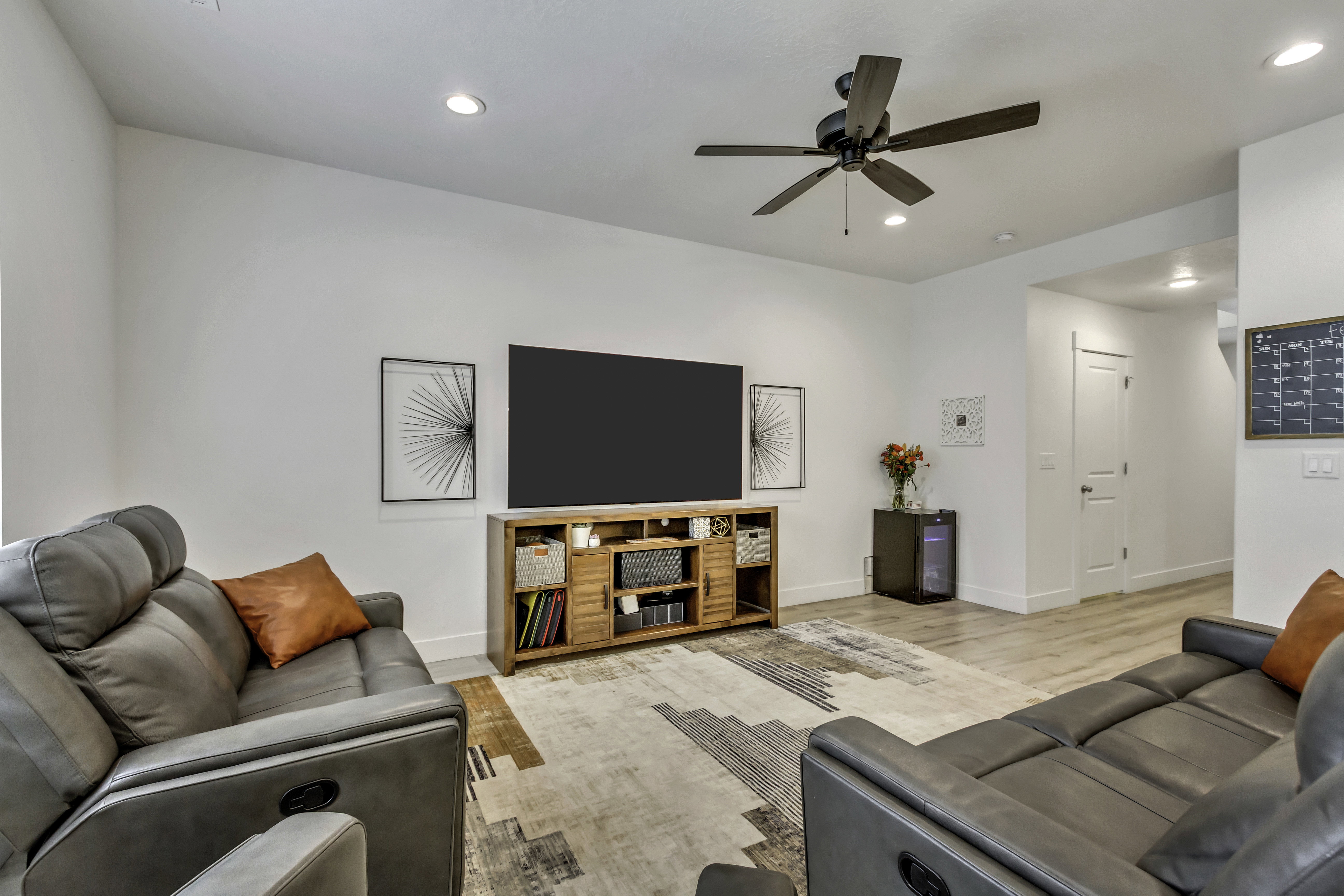 Open-concept living space featuring a ceiling fan, recessed lighting, wood-finish flooring, white baseboards, and a solid white door