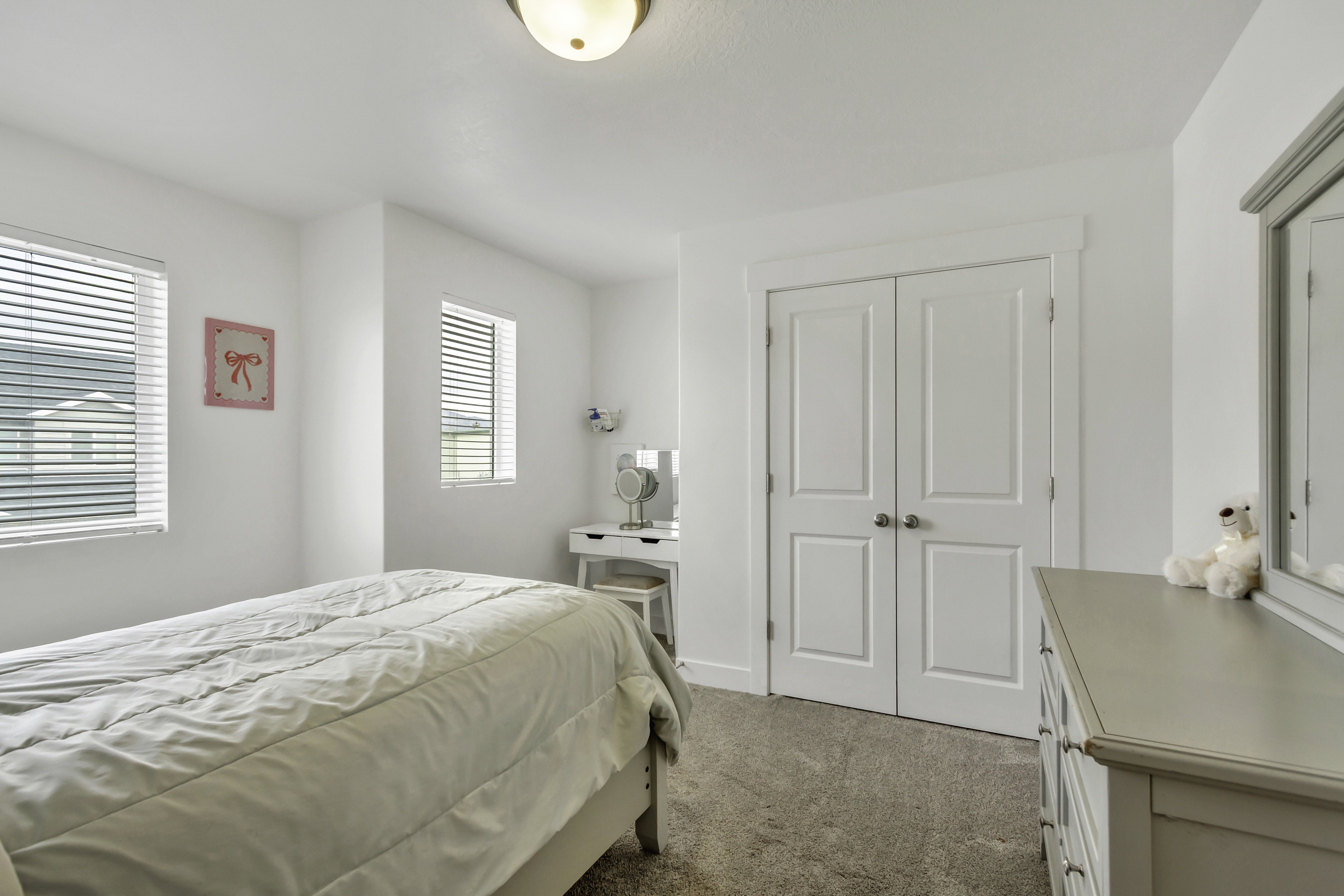 Carpeted room featuring multiple windows with blinds, a double-door closet, and a ceiling-mounted light fixture