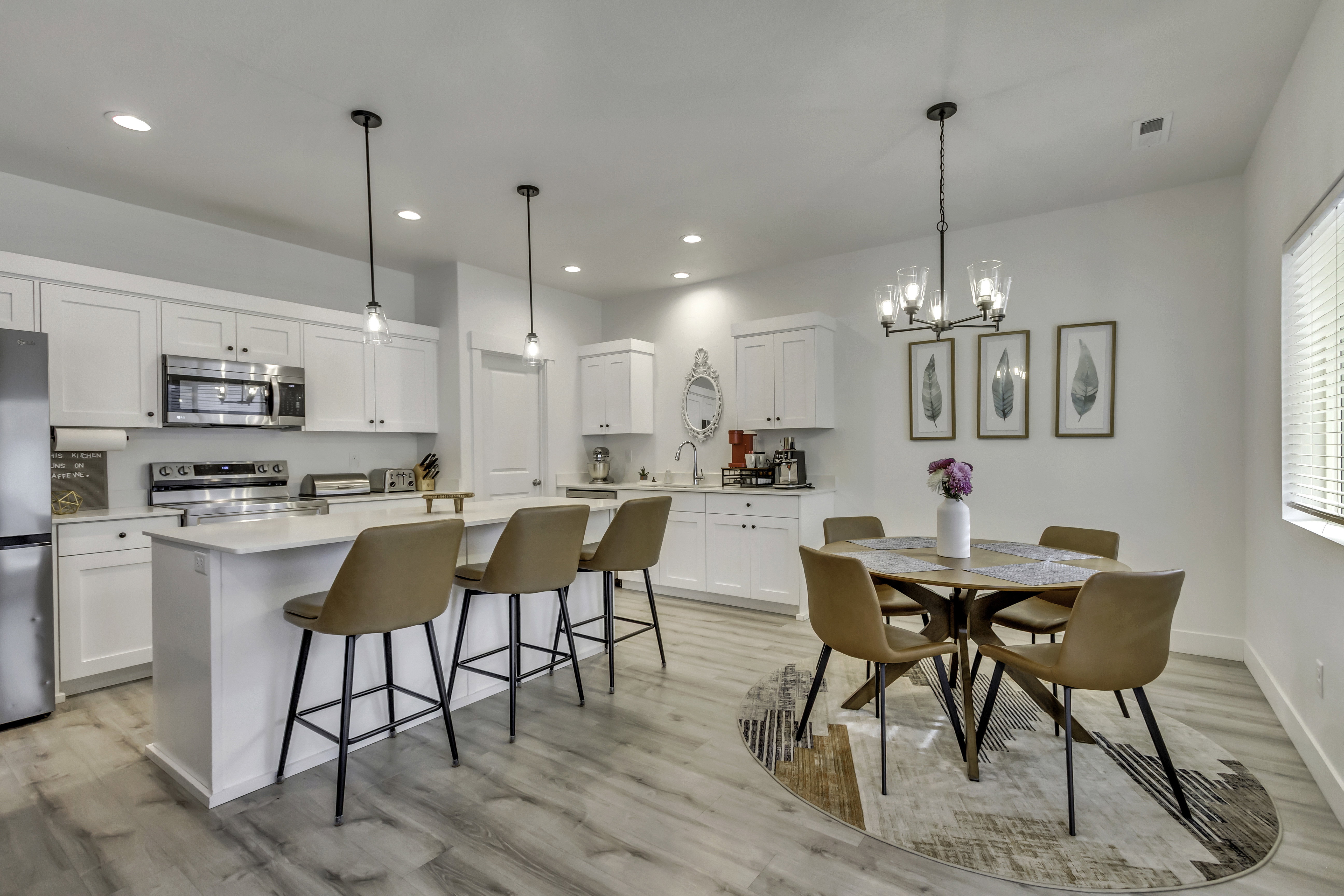 Kitchen featuring white cabinetry, stainless steel appliances, a white island with pendant lighting, and wood-finish flooring