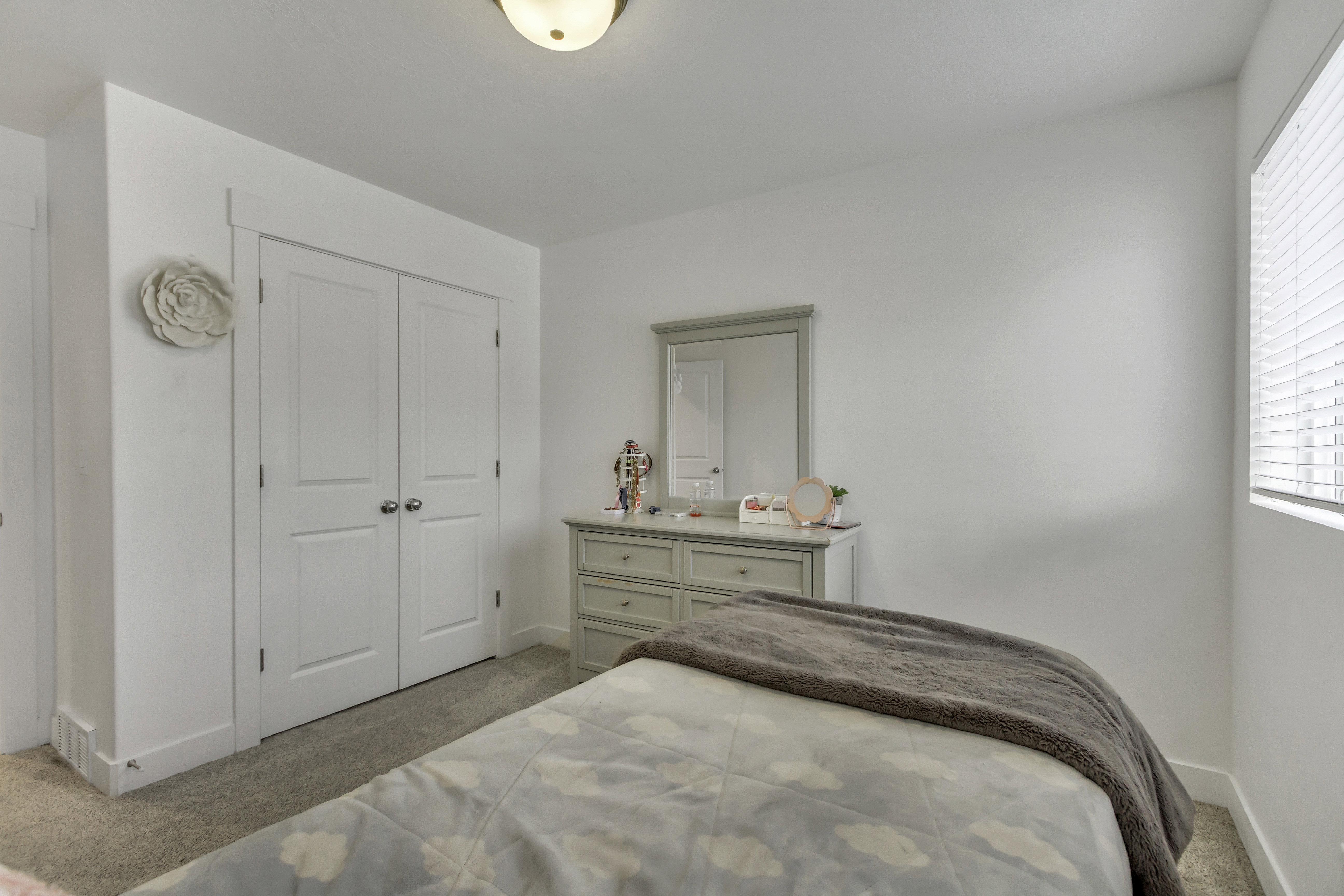 Neutral paint palette, carpeted flooring, window with blinds, and white bi-fold closet doors with chrome hardware