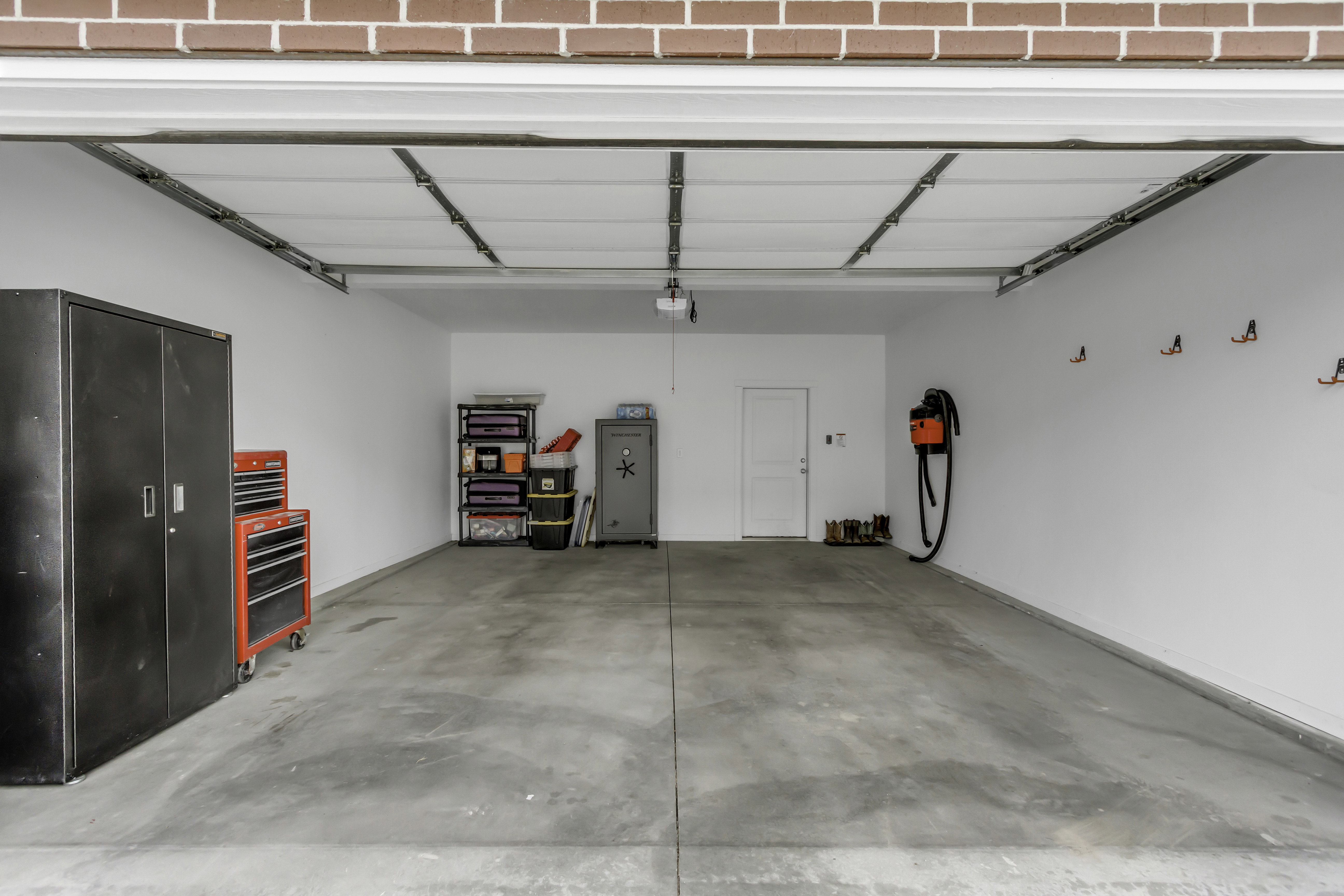 Spacious garage with concrete flooring, white painted walls, and a convenient side access door