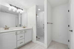 Bathroom featuring a dual vanity with light-toned countertops, white cabinetry, and brushed nickel hardware