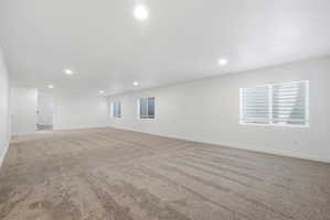 Expansive open room featuring plush carpeting, recessed lighting, and bright white walls