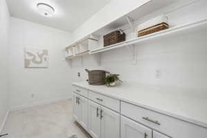 Bright utility room featuring white cabinetry, light countertops, and light-toned flooring