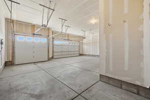 Spacious multi-car garage featuring two white sectional garage doors with upper window panels