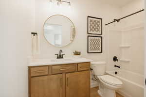 Bathroom featuring a wood-finish vanity with a white countertop, an undermount sink, and a matte black faucet