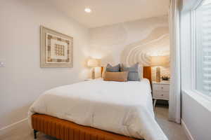 Bedroom featuring a patterned accent wall, recessed lighting, a modern window with blinds, and light-toned carpeting