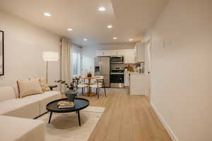 Open-concept living space featuring wood-finish flooring, recessed lighting, and a modern kitchen