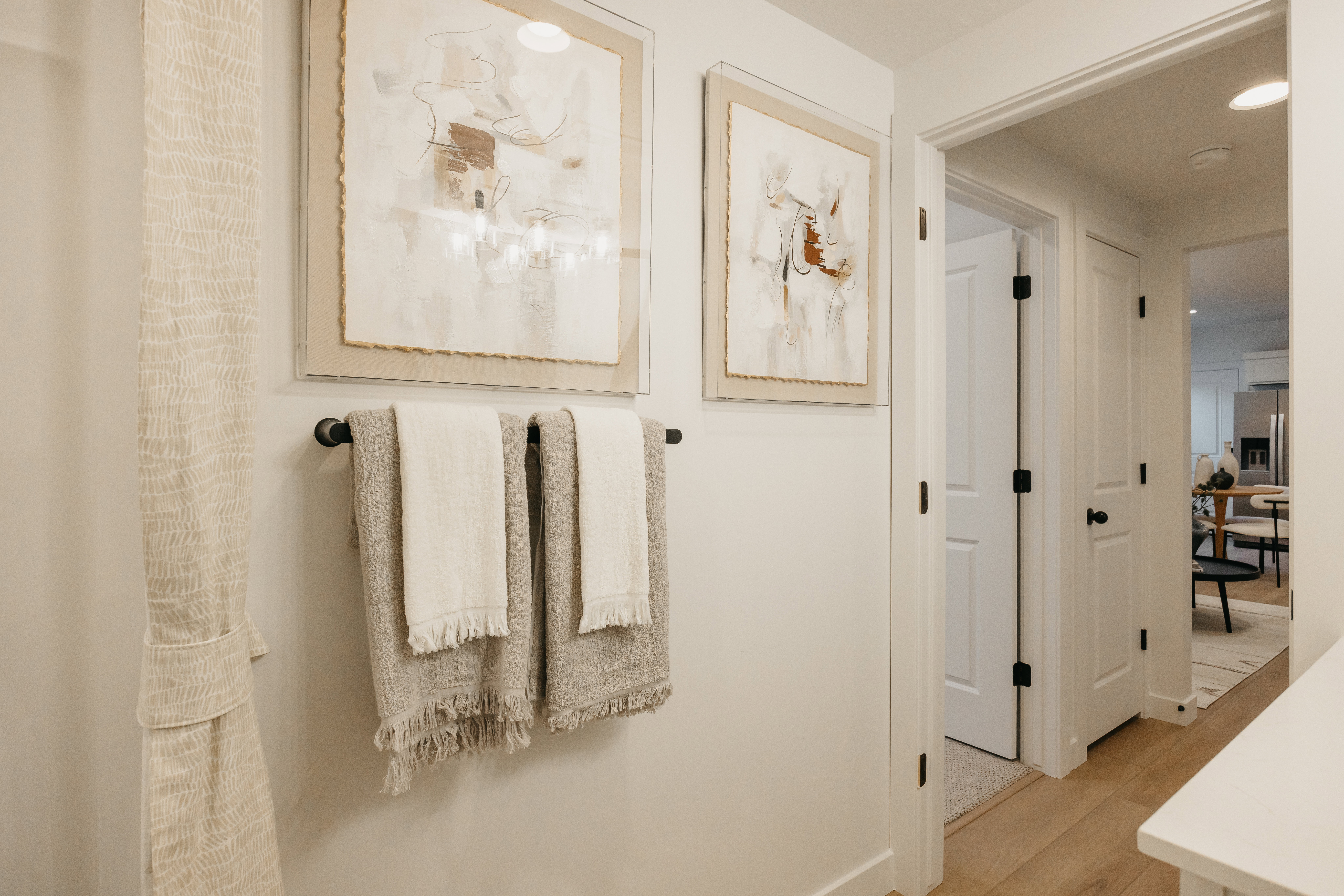 Bright hallway featuring light wood-finish flooring and crisp white walls