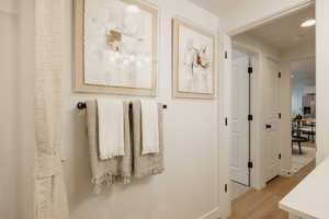 Bright hallway featuring light wood-finish flooring and crisp white walls