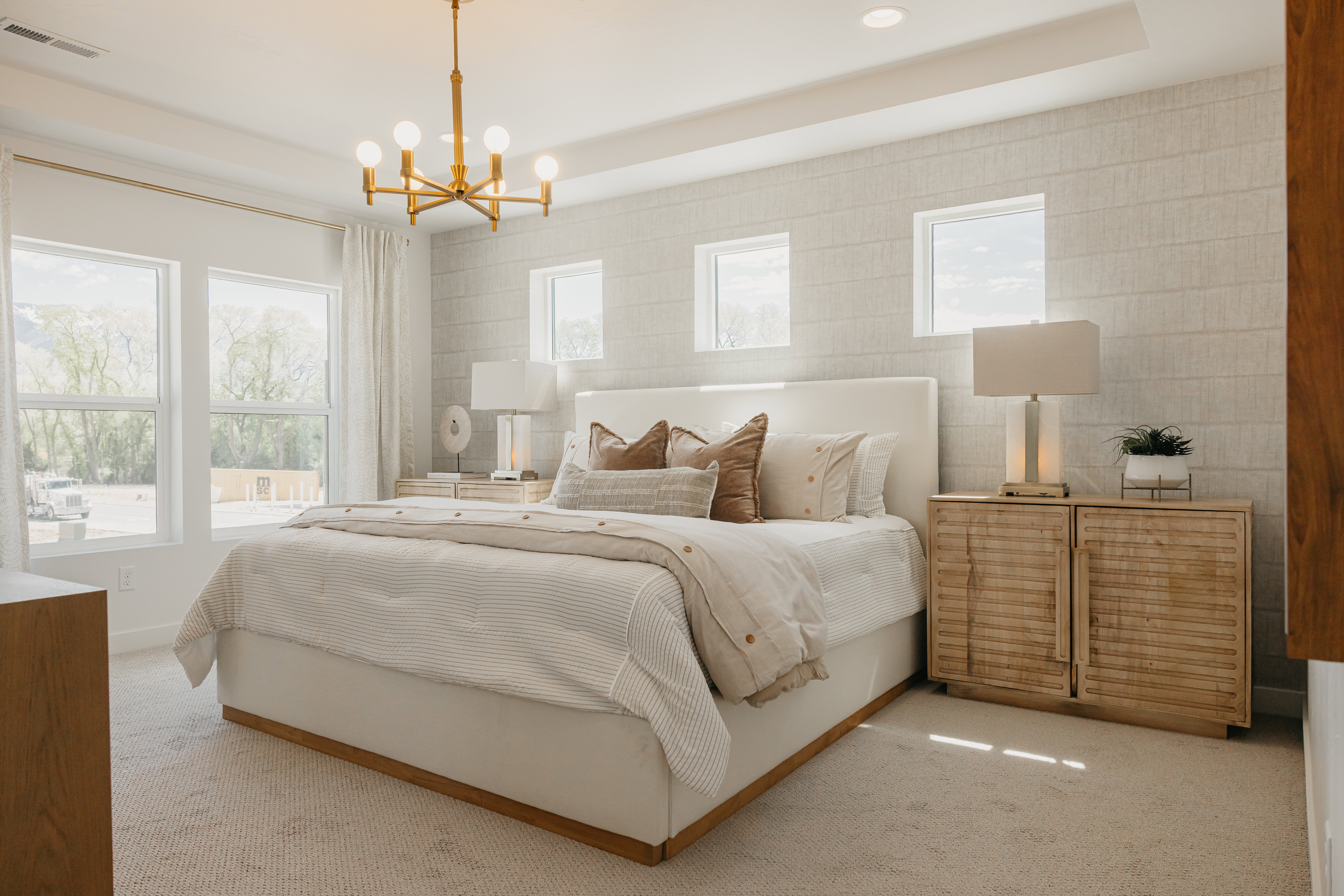 Spacious sleeping area featuring a tray ceiling, recessed lighting, and a contemporary brass chandelier