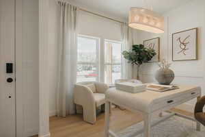 Bright interior room with wood-finish flooring, featuring a statement pendant light fixture and white walls with decorative paneling